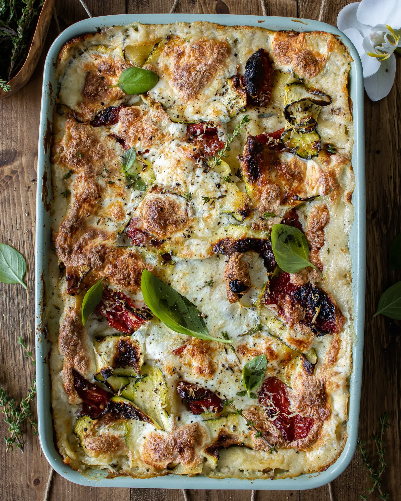 Overhead shot of Spinach, Zucchini and Sun-dried Tomato Lasagna freshly baked in a pale mint rectangular ceramic baking dish