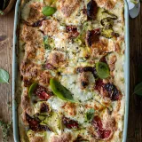 Overhead shot of Spinach, Zucchini and Sun-dried Tomato Lasagna freshly baked in a pale mint rectangular ceramic baking dish