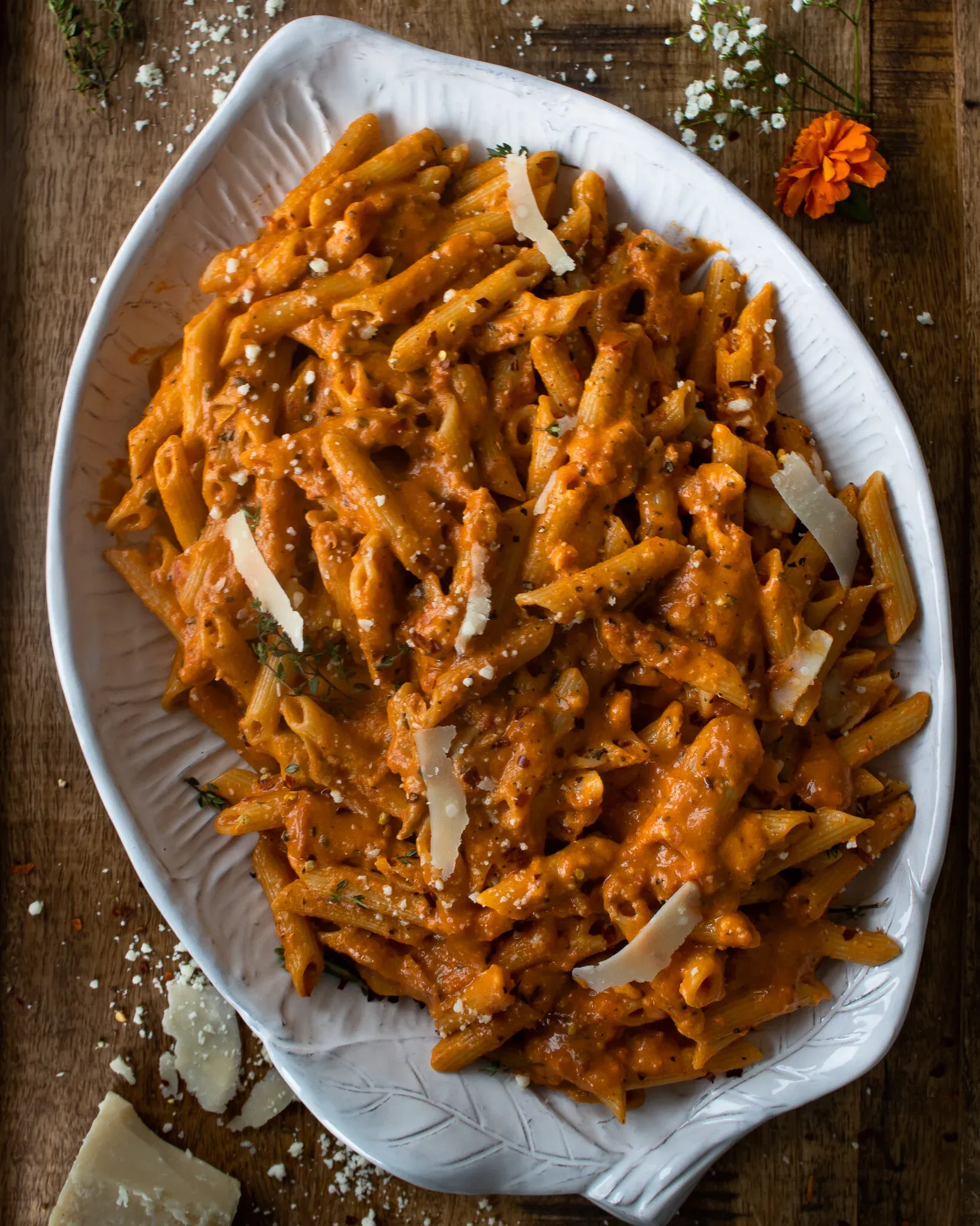 Pasta Alla Vodka piled on a white embossed oval ceramic serving platter on dark wood