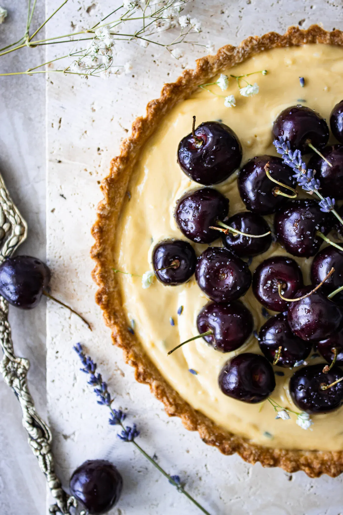 Close-up overhead view of a lavender vanilla tart with a golden fluted shortcrust pastry shell filled with pale yellow vanilla cream