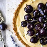 Close-up overhead view of a lavender vanilla tart with a golden fluted shortcrust pastry shell filled with pale yellow vanilla cream