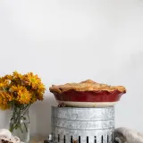 Side-angle portrait of a Classic Apple Pie baked in a deep red ceramic pie dish