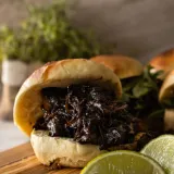 BBQ Beef Slider stacked with dark, glossy saucy shredded chuck beef on a soft golden bun
