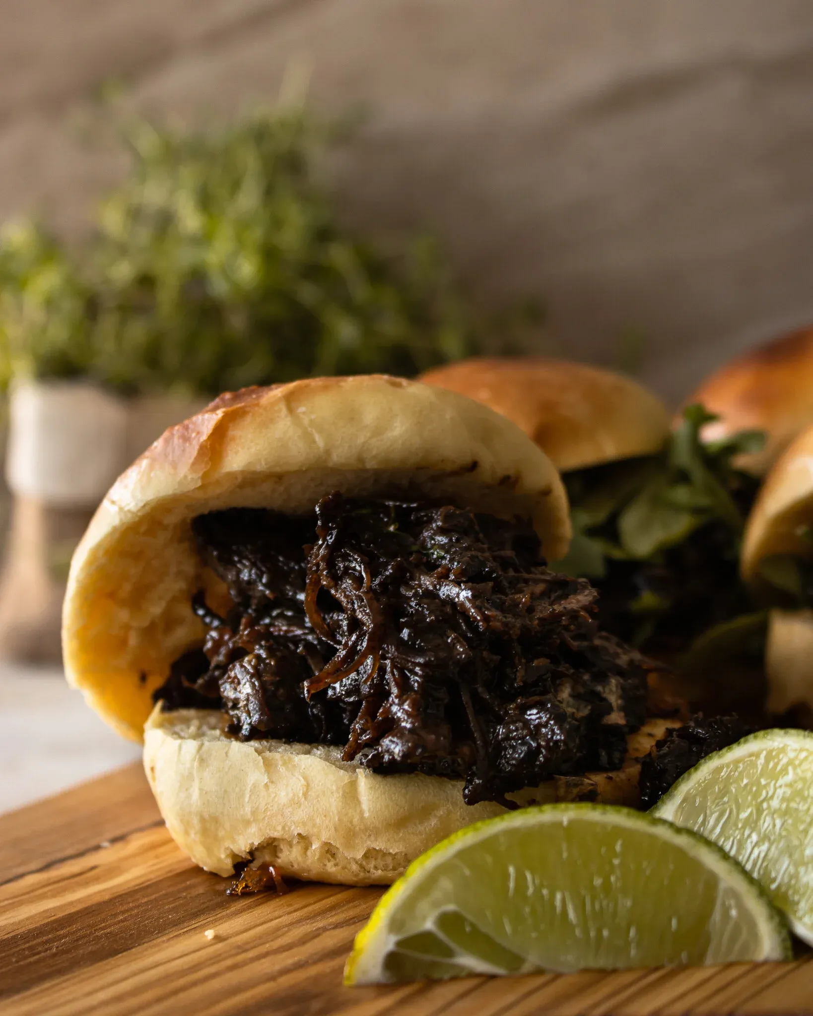 BBQ Beef Slider stacked with dark, glossy saucy shredded chuck beef on a soft golden bun