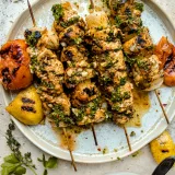 Five Citrus and Mojo Marinated Grilled Chicken Skewers fanned across a rustic white ceramic plate