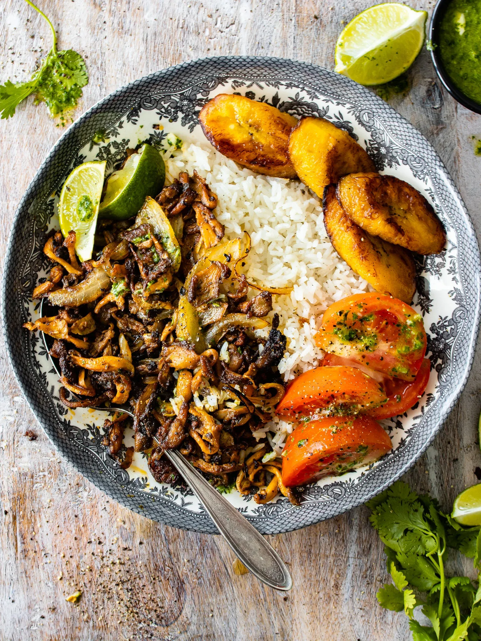 Oyster Mushroom Vaca Frita plated on a vintage blue-gray floral ceramic dish on a weathered white wood surface