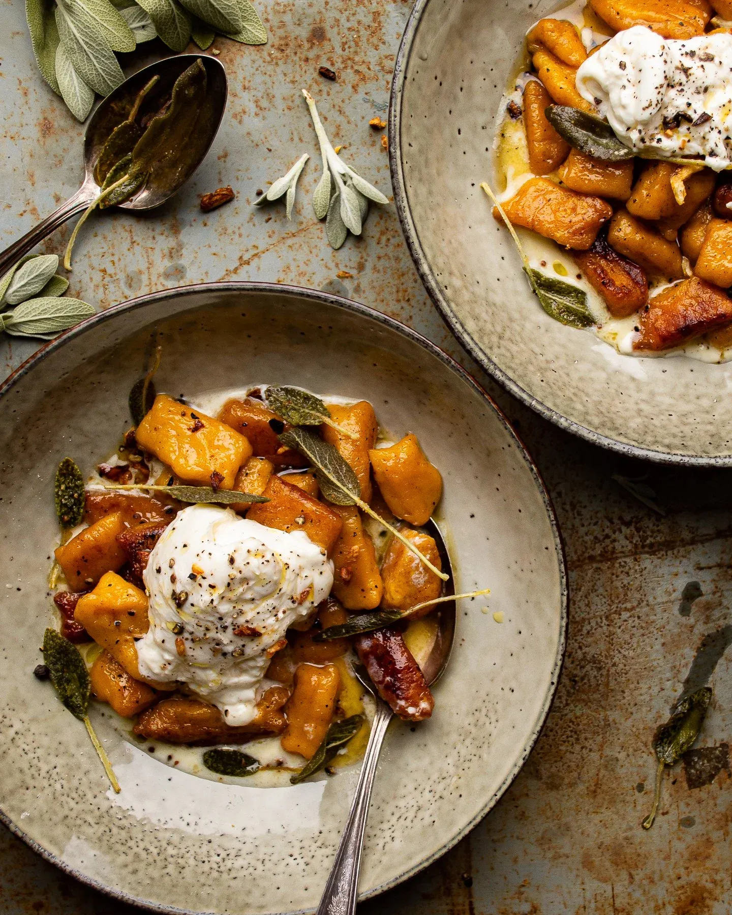 Two speckled ceramic bowls of kabocha squash gnocchi in maple brown butter sauce