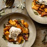 Two speckled ceramic bowls of kabocha squash gnocchi in maple brown butter sauce