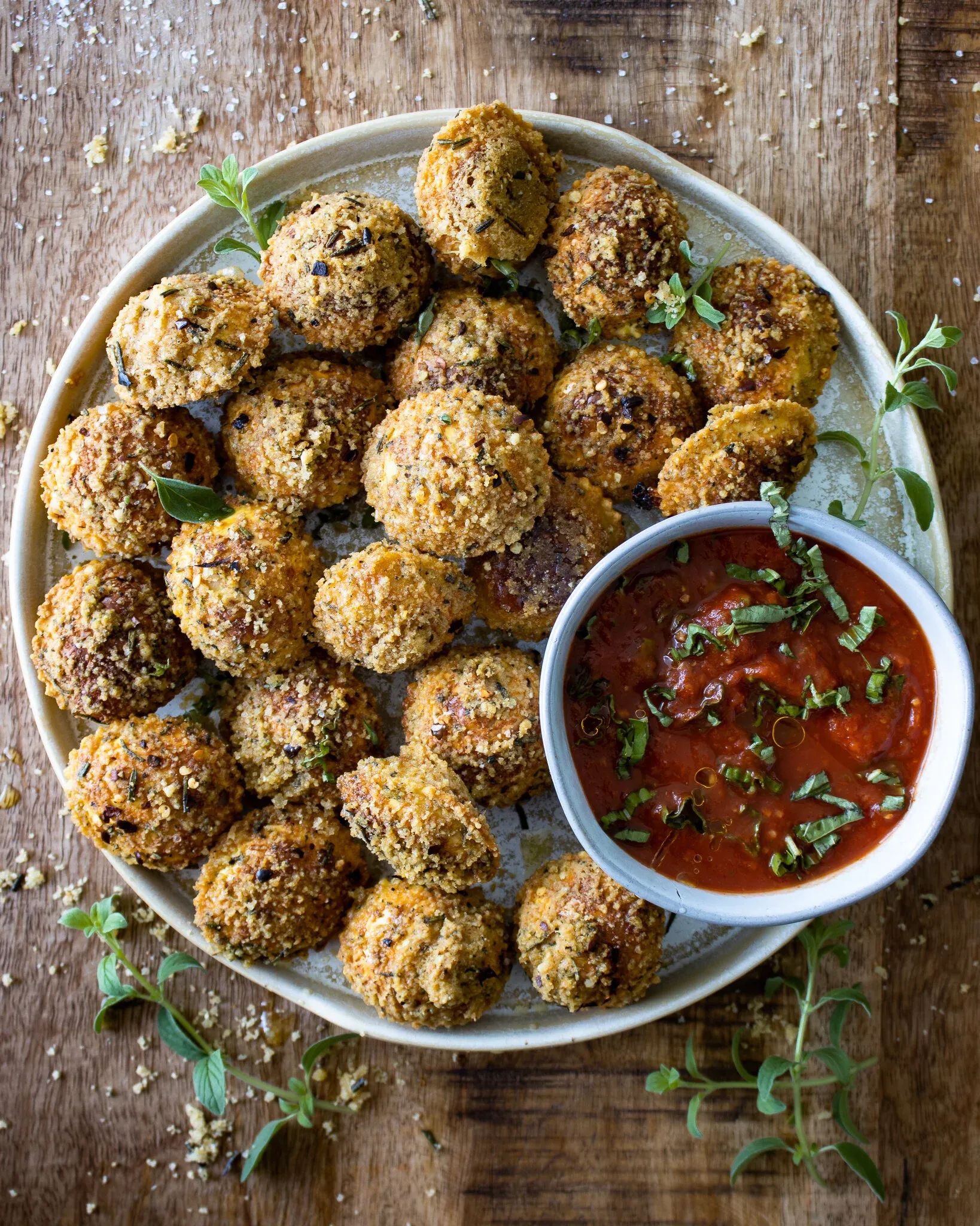 Oven Baked Fried Ravioli piled on a round stoneware plate on a dark wooden surface — dozens of golden