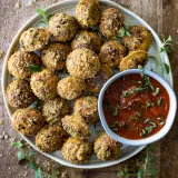 Oven Baked Fried Ravioli piled on a round stoneware plate on a dark wooden surface — dozens of golden