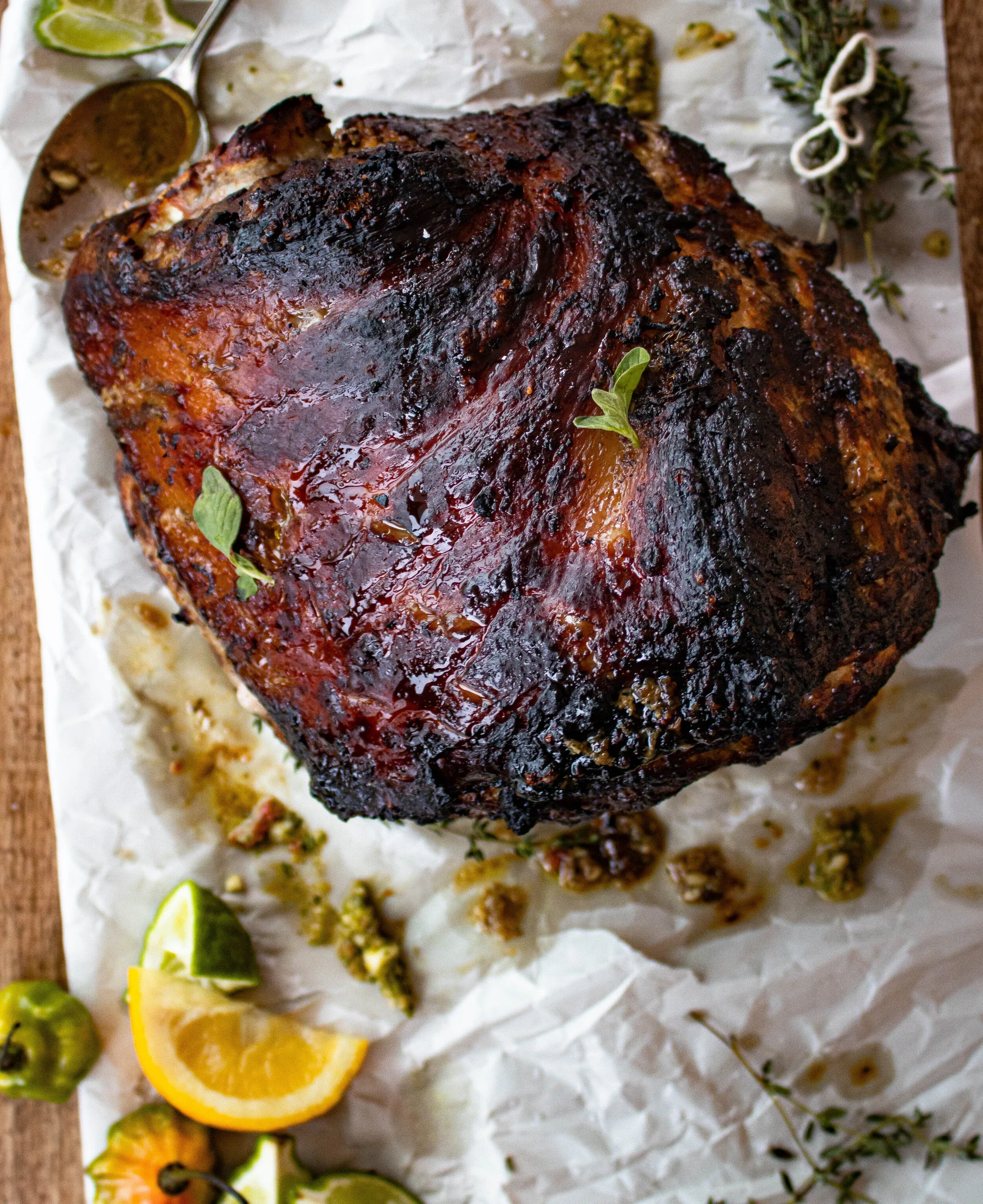 Whole puerco asado roast pork shoulder resting on crinkled parchment on a wooden surface