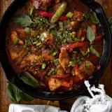 Overhead view of cast iron Asian-inspired spicy fish in a large black cast iron skillet on a dark wooden surface