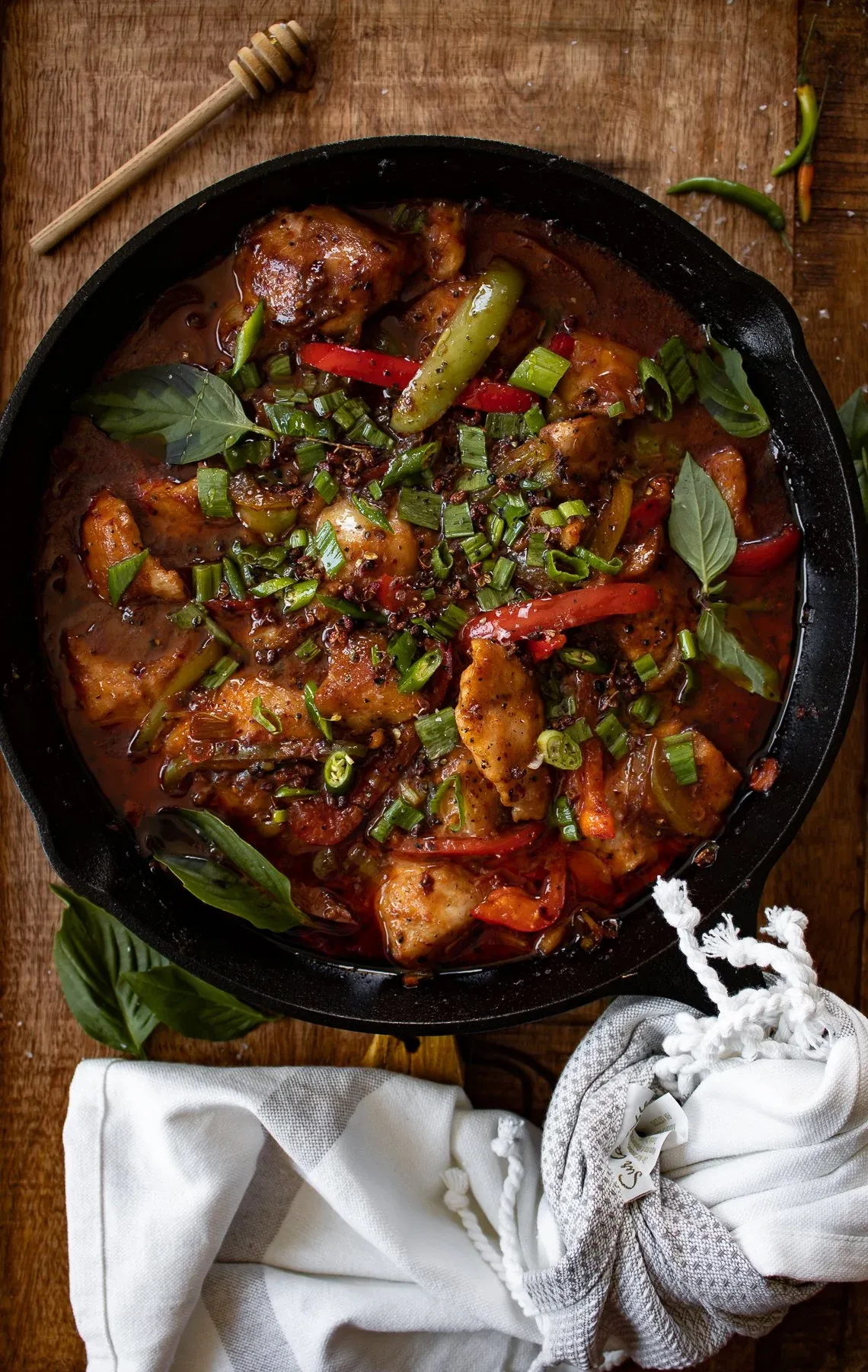 Overhead view of cast iron Asian-inspired spicy fish in a large black cast iron skillet on a dark wooden surface