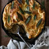 Overhead view of a chicken pot pie baked in a large black cast iron skillet on a dark wooden board