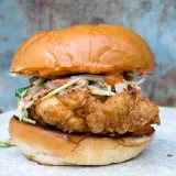 Fried Chicken Sandwich with Creamy Slaw and Sriracha Aioli served on a golden toasted brioche bun