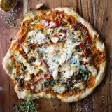 Overhead view of a whole chicken alla vodka pizza on a rustic wooden board