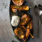 Overhead shot of a dark oval metal platter filled with maple roasted squash wedges