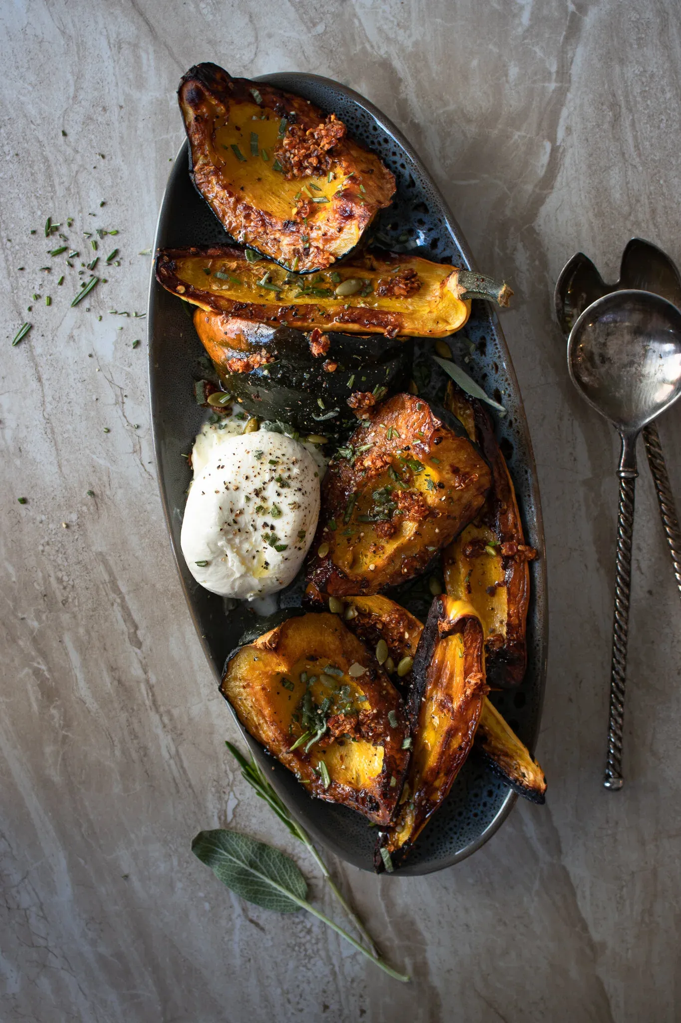Overhead shot of a dark oval metal platter filled with maple roasted squash wedges