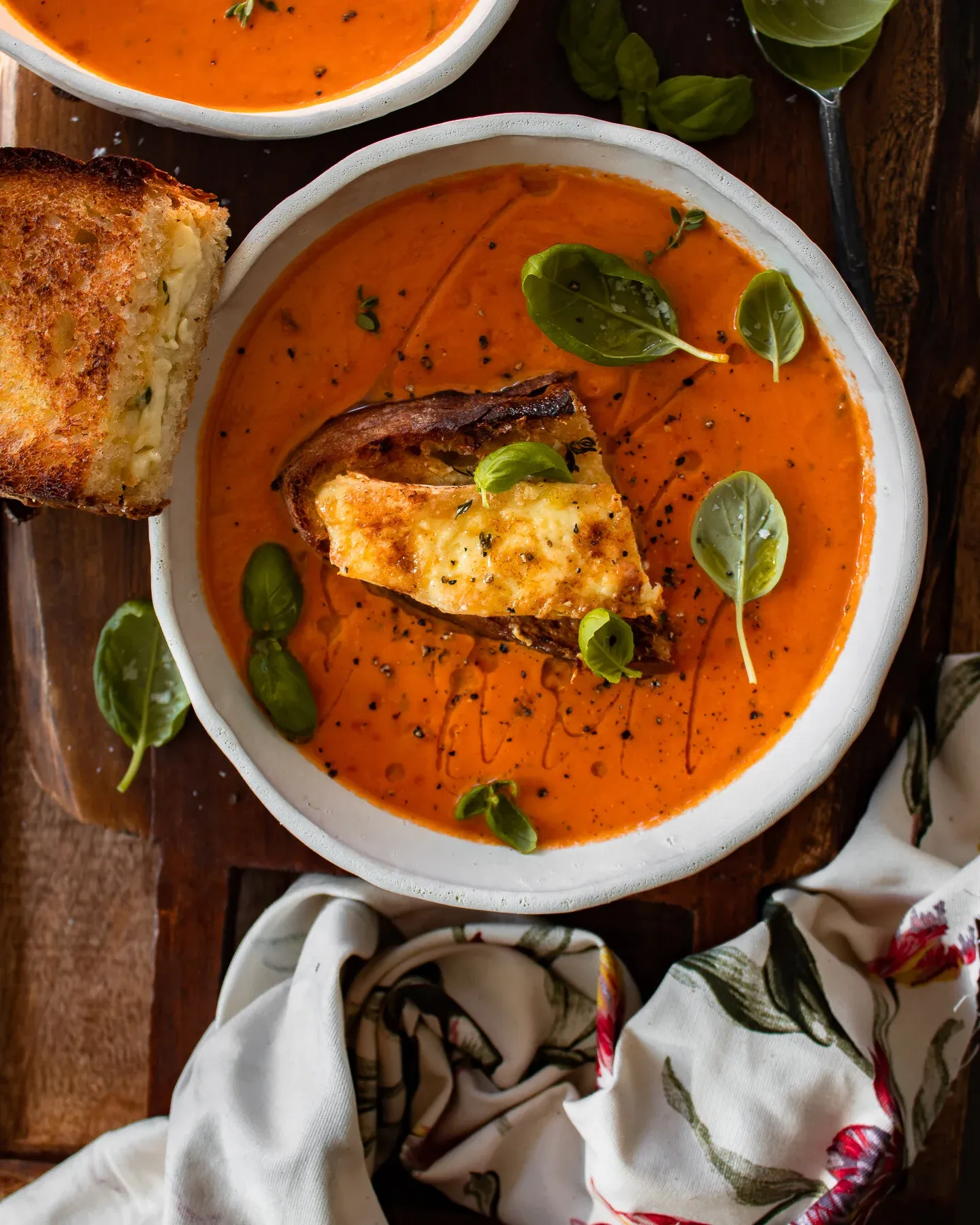 One Pot Roasted Tomato and Herb Soup with Halloumi Toast in a white ceramic bowl, overhead view on a dark wooden board