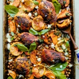Overhead view of a dark sheet pan of Sheet Pan Harissa Chicken with Sweet Potatoes and Chickpeas