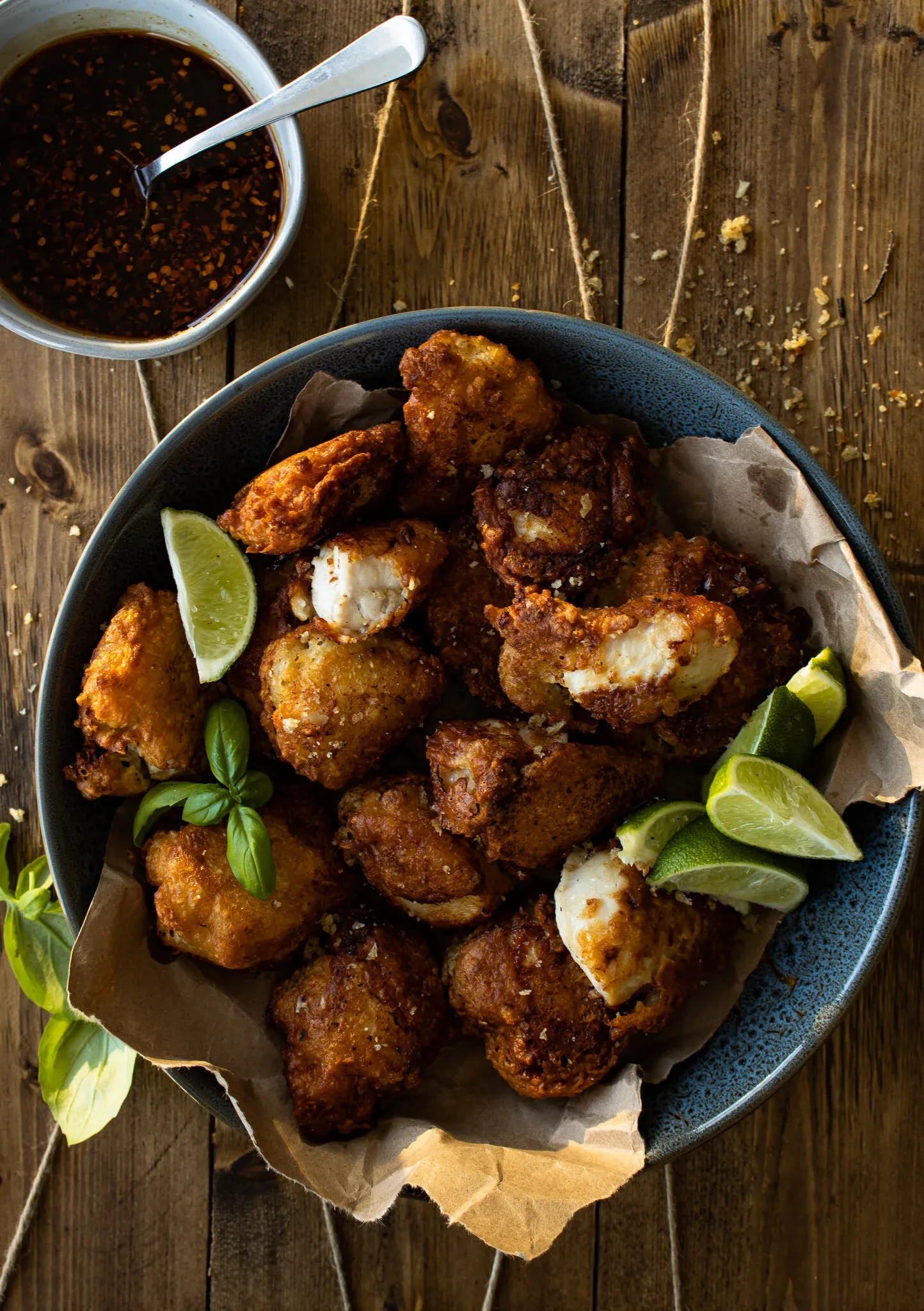 Batter Fried Chicken pieces piled in a dark blue ceramic bowl lined with parchment paper