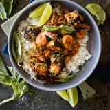 Overhead view of a gray bowl of Honey Garlic Salmon and Shrimp Bowl on a dark metal surface