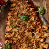 Overhead portrait view of a fully baked Christmas Tree Pull Apart Bread on crinkled parchment paper on a dark wood board