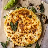 Overhead view of a whole uncut Wild Mushroom and Pesto Quesadilla on brown parchment paper