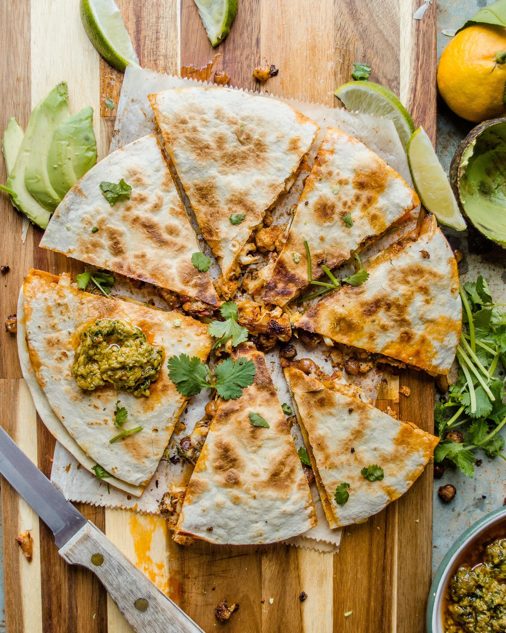 Crispy Chickpea and Cauliflower Quesadilla sliced into eight wedges and arranged overhead on a striped wooden cutting board