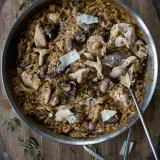 One Skillet Chicken and Mushroom Orzo with Creamy Tarragon Sauce served in a large stainless steel skillet resting on a round wooden cutting board