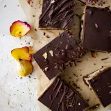 Overhead flat-lay of six No Bake Dark Chocolate Peanut Butter Oat Bars on parchment paper over a white marbled surface