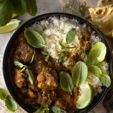 Overhead shot of a matte black bowl of Quick Coconut Curry Chicken on a gray concrete surface