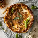 Overhead view of a whole sweet potato, spinach and caramelized onion phyllo pie with a deeply golden