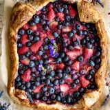 Overhead flat-lay of a square puff pastry berry galette on parchment paper