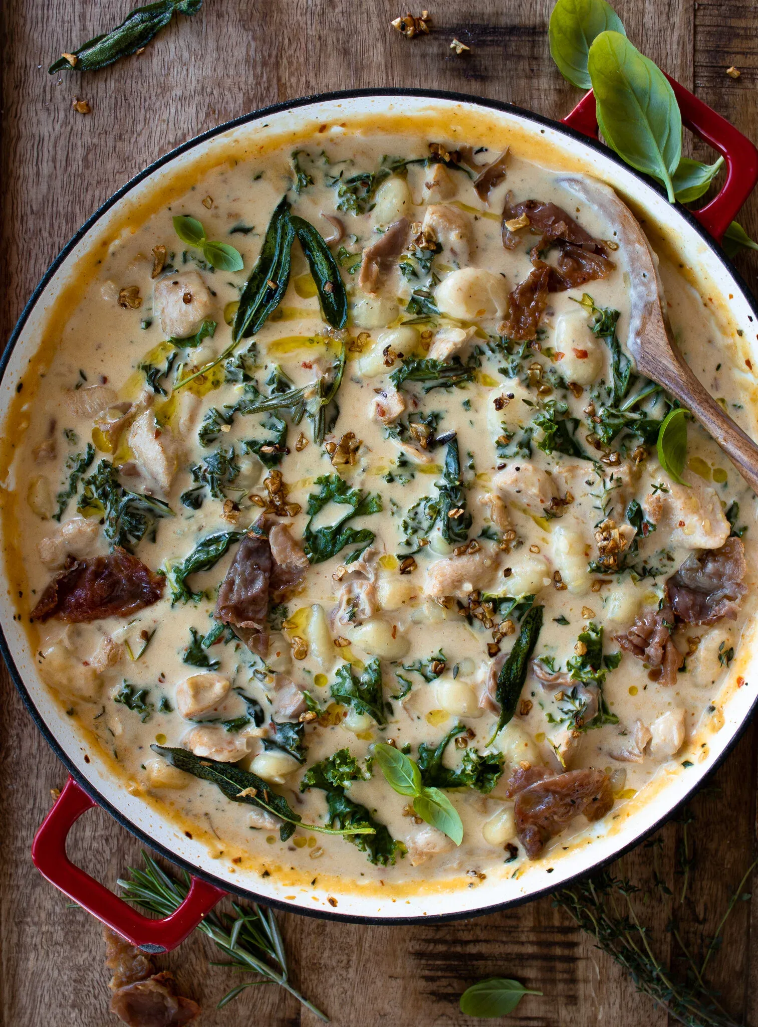 Overhead view of One Pot Gnocchi Soup with Kale and Prosciutto in a large red-handled white enamel braiser