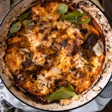 Short Rib Skillet Lasagna baked in a large round white enamel braiser with charred black rim